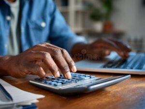 persona usando computadora con calculadora y papeles